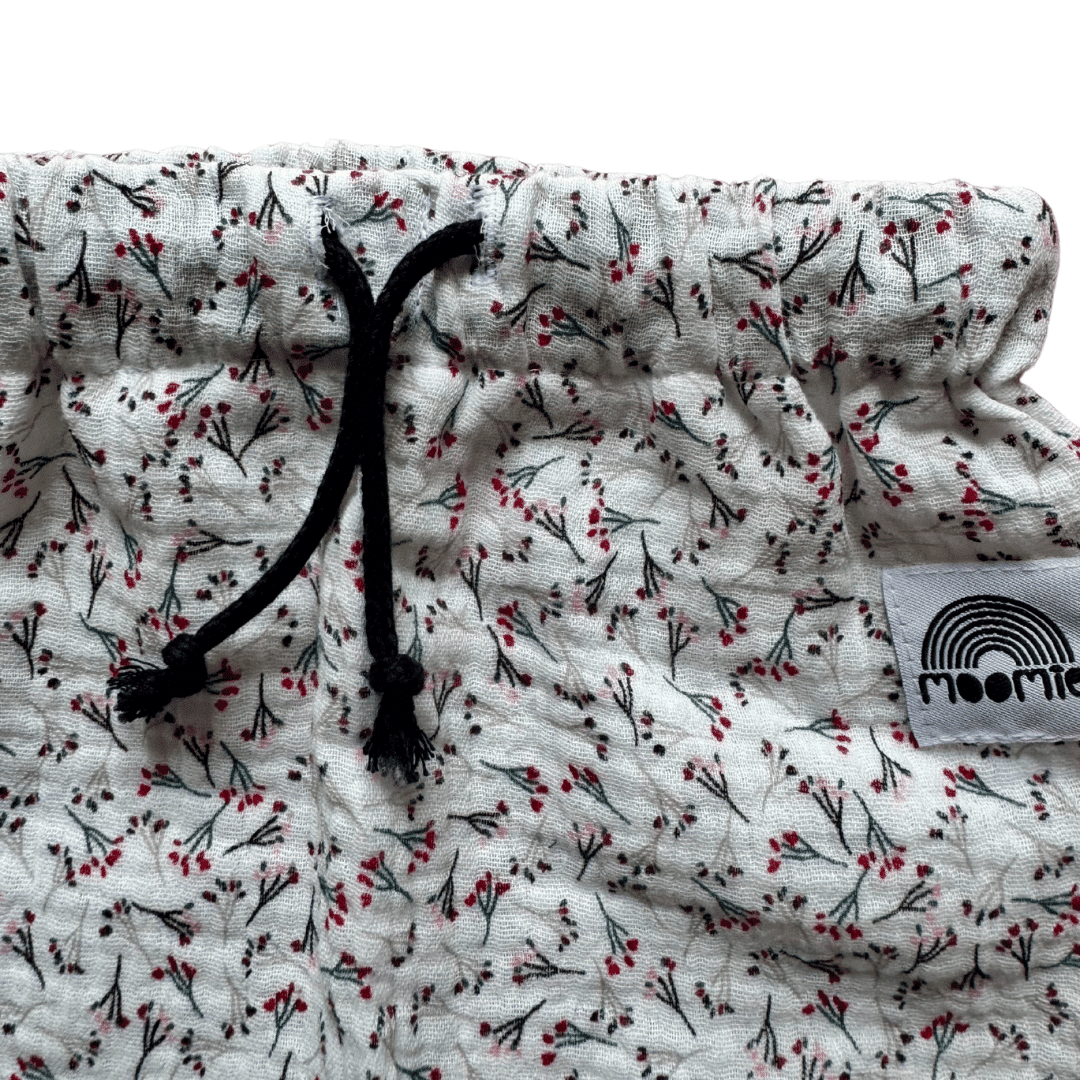 Gros plan sur la taille élastiquée avec cordon de serrage du pantalon bébé en gaze de coton imprimé bouquets.