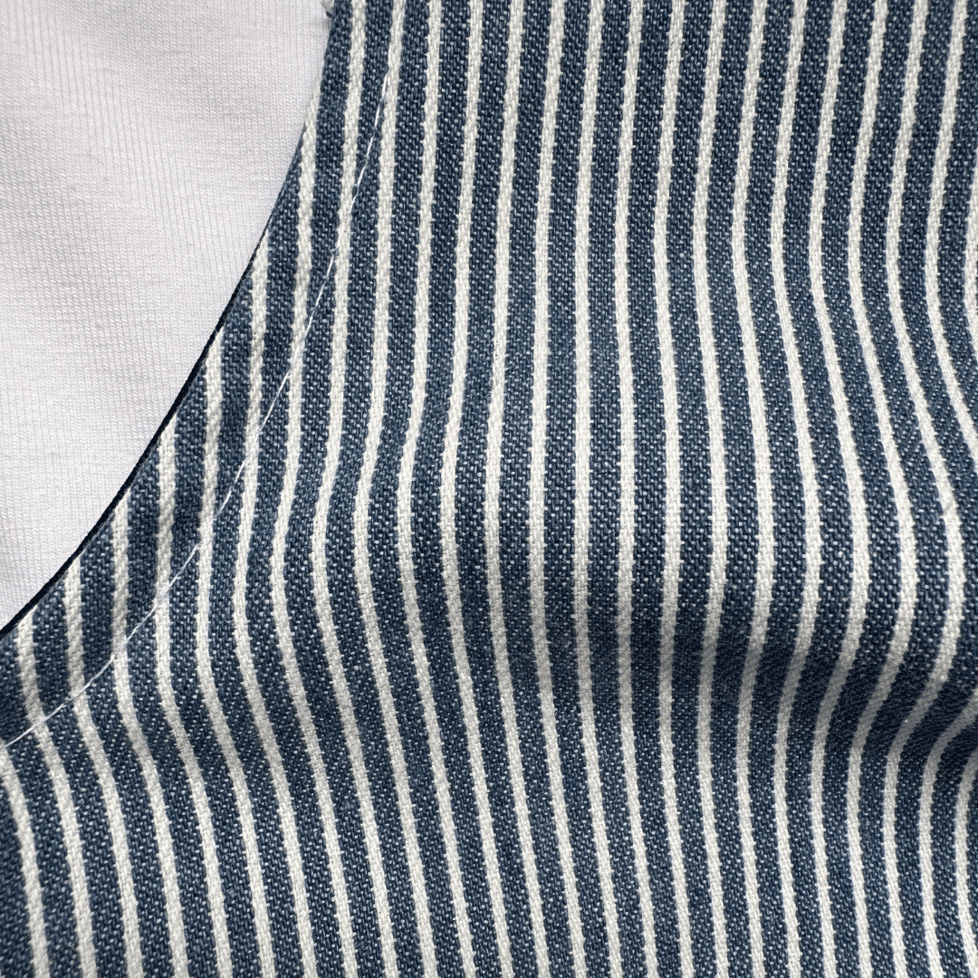 Zoom sur le tissu rayé bleu et écru en coton d’une salopette bébé fabriquée en France par Moomie