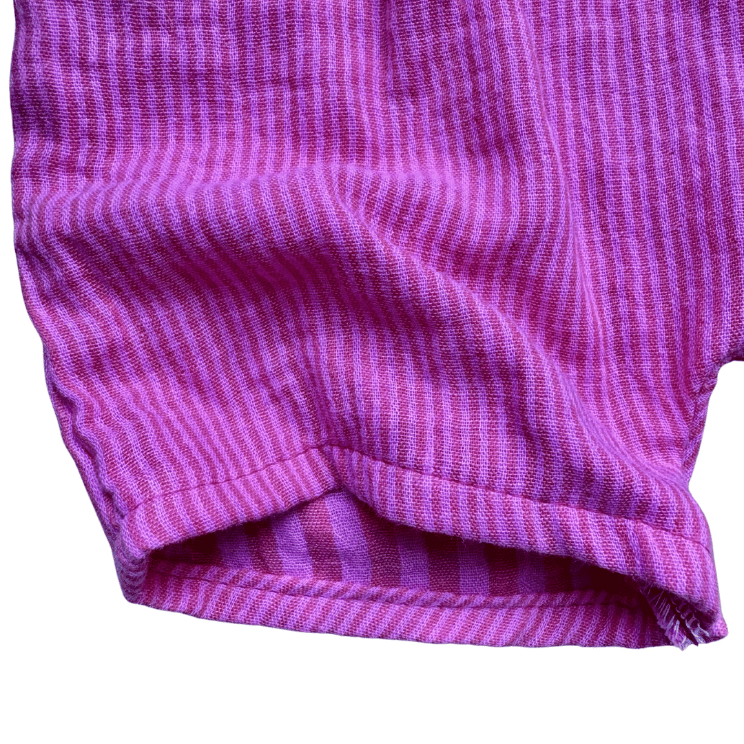 Zoom sur ourlet et tissu du short bébé en gaze de coton rayé fuchsia et rose