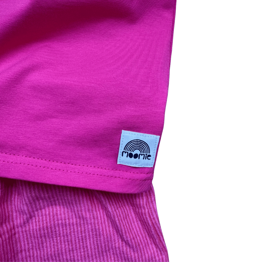 Gros plan sur la matière et l’étiquette du t-shirt enfant fuchsia Moomie