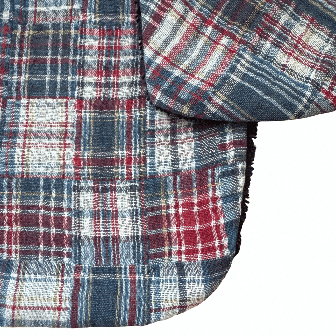 Détail du motif patchwork à carreaux bleu, écru et bordeaux sur bavoir bébé en coton