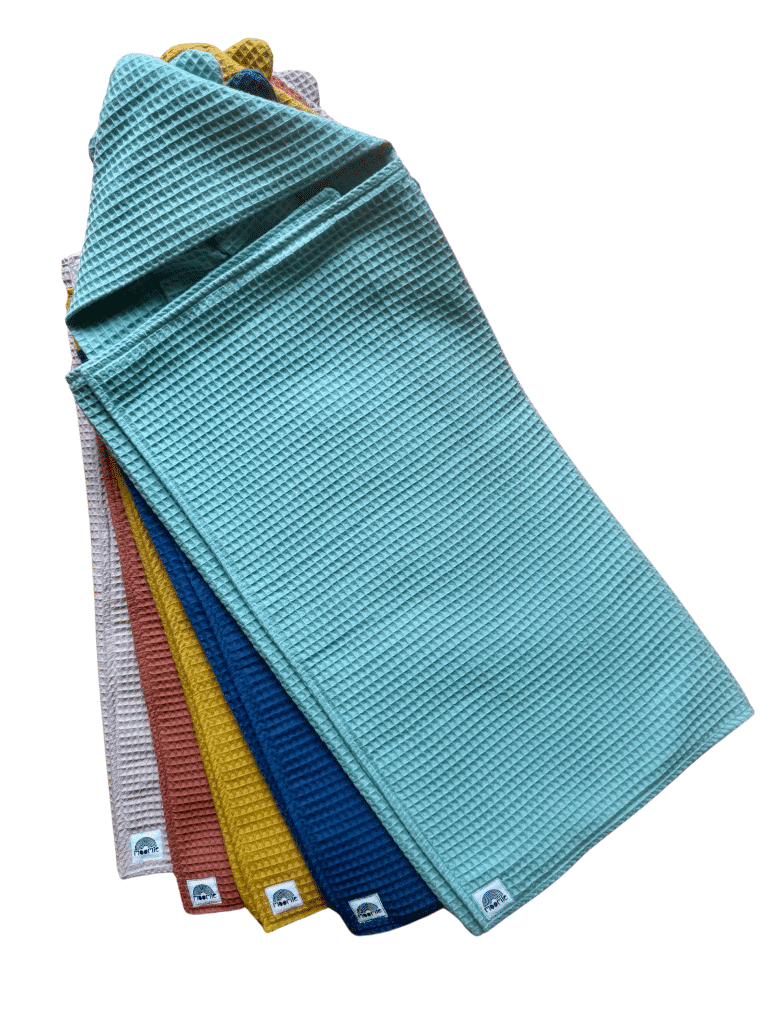 Sélection de capes de bain bébé en coton nid d’abeille Moomie, fabriquées en France, présentées dans différents coloris pastel et colorés.
