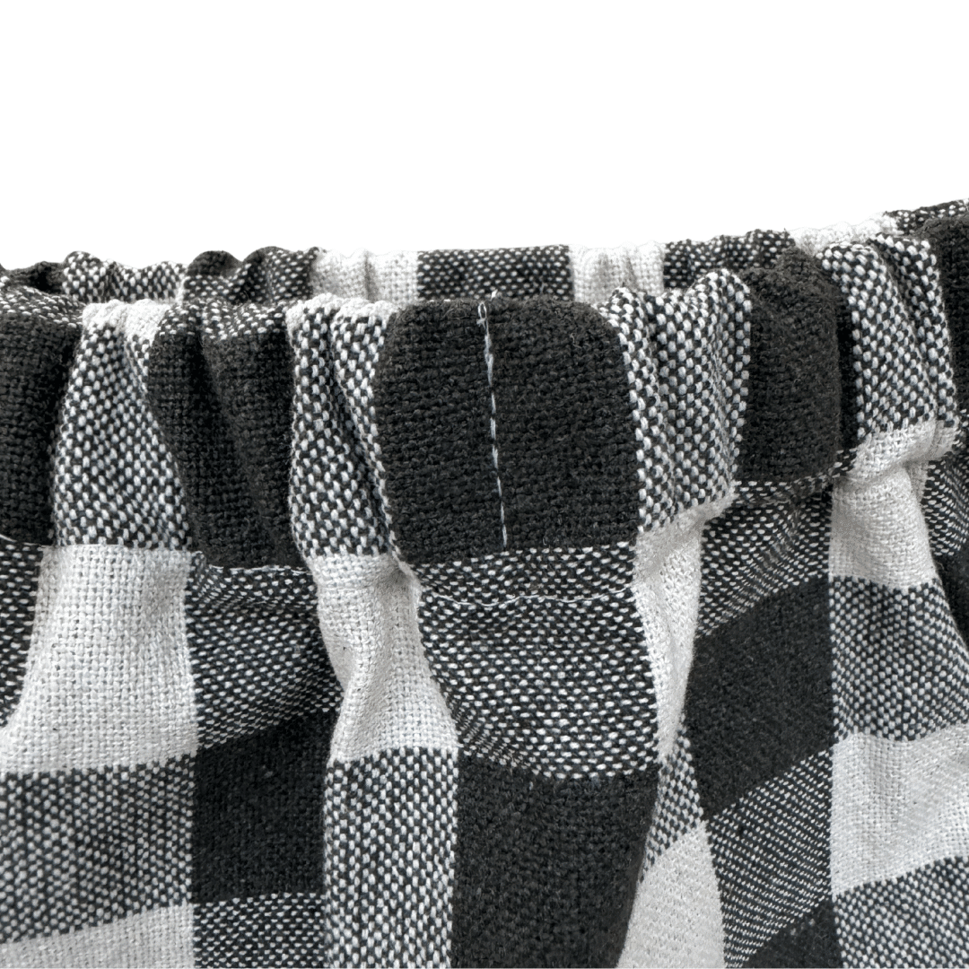 Gros plan sur la taille élastiquée du pantalon bébé à carreaux kaki et écru