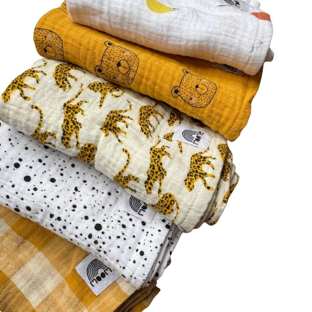 Détail des langes bébé en gaze de coton aux motifs léopards, ours et tons moutarde